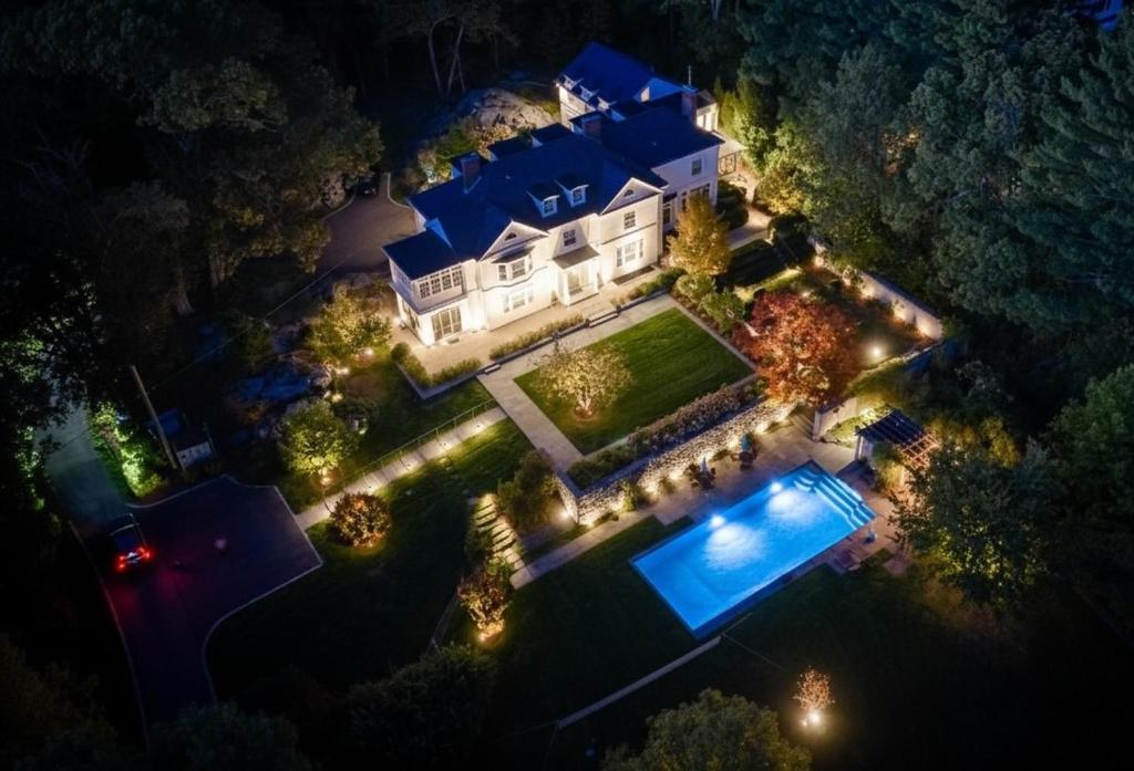 an aerial view of a house with a swimming pool at night at Lavish Boston Mansion Pool, Gardens, Games, Pond! in Dedham