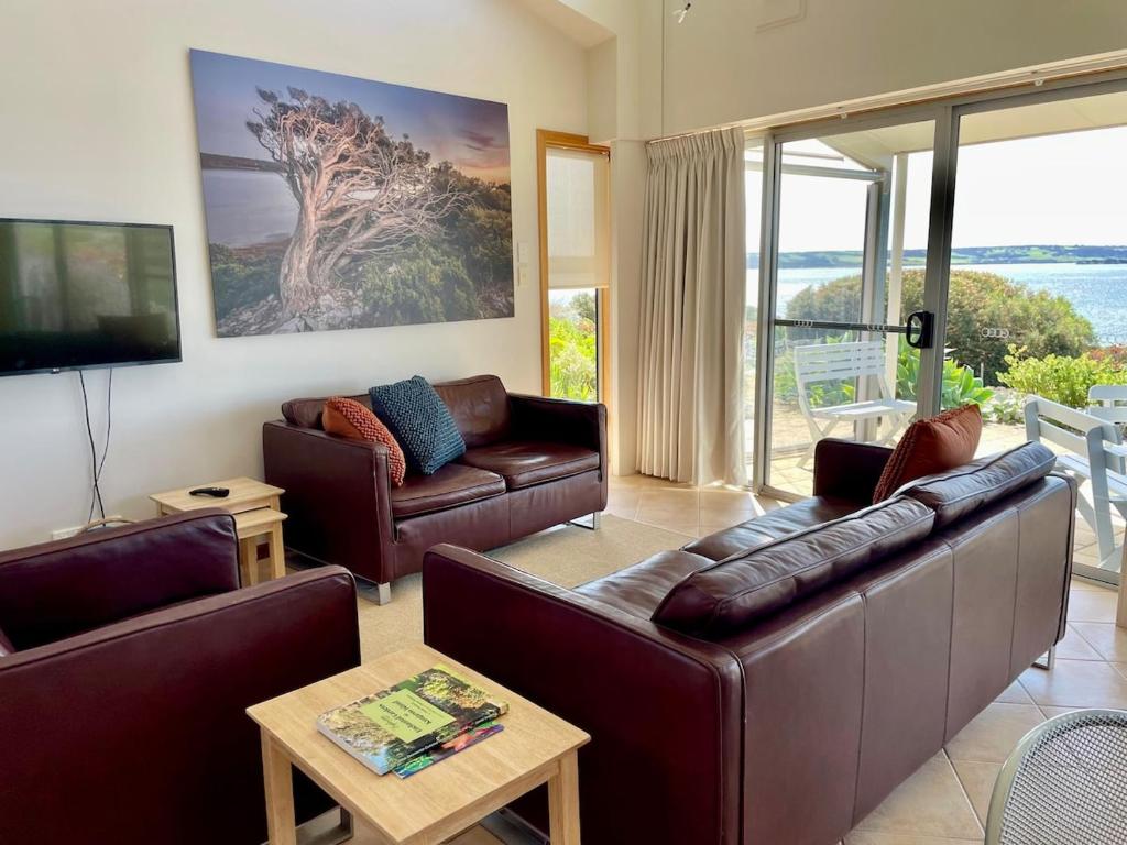 a living room with leather couches and a tv at Moonrise Cove in Pelican Lagoon
