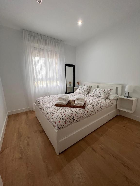 a white bedroom with a white bed and a window at Casa Rural Las Candelas in San Vicente de Alcántara