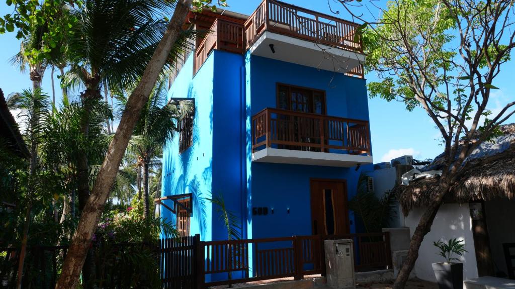a blue house with a balcony and palm trees at Loft Jeri Premium in Jericoacoara