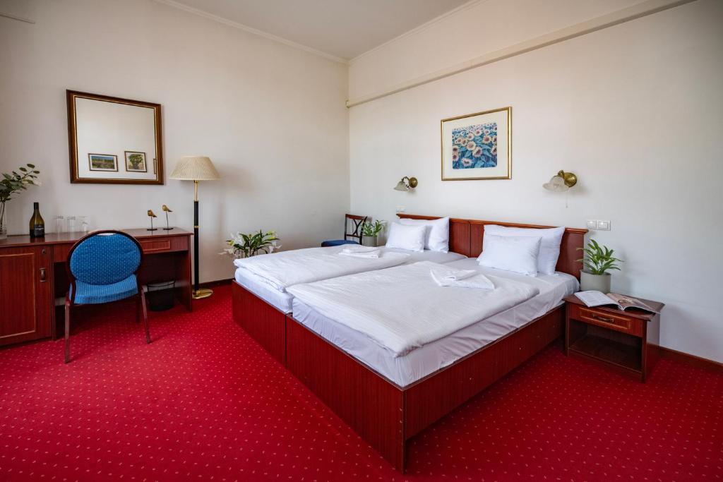 a bedroom with a bed and a desk and a chair at Mádi Kúria Hotel és Rendezvényközpont in Mád