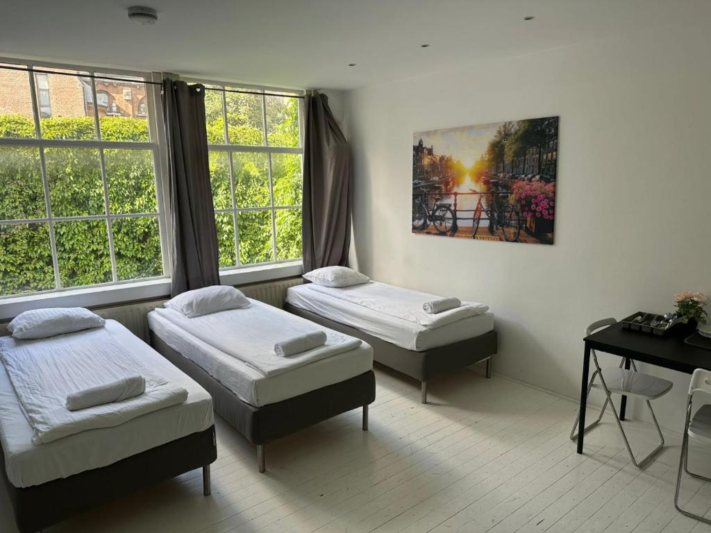 a room with two beds and a desk and windows at Amsliving in Amsterdam
