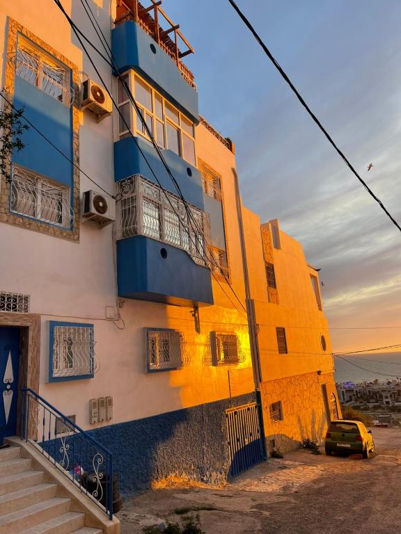 a yellow and blue building with a car parked next to it at Cool Wave Morocco in Tamraght Ouzdar