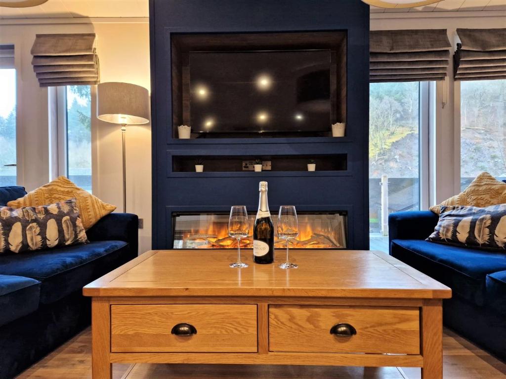 een woonkamer met een fles wijn en twee glazen op een salontafel bij High Spy Luxury Lodge in Keswick