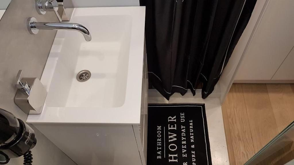 a white sink with a black curtain and a sign at Studio Ten in Thessaloniki