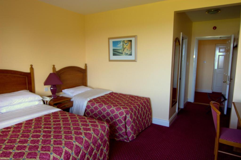 um quarto de hotel com duas camas e uma mesa com um candeeiro em Lavelle's Seaside House & Mickey's Bar em Achill Sound