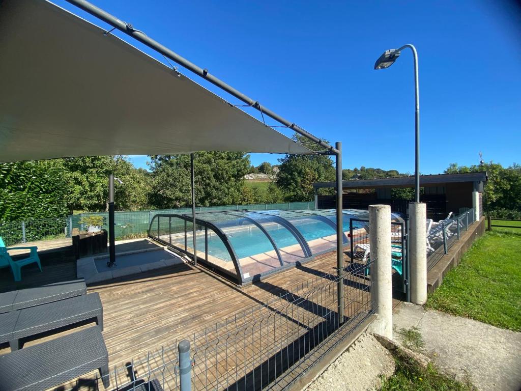 a swimming pool with a wooden deck and a fence at Gîte de la Taouyre in Saint-Symphorien-de-Thénières