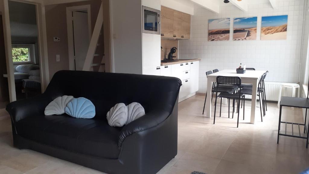 a living room with a black couch with pillows on it at a l'aise aan zee in Koksijde