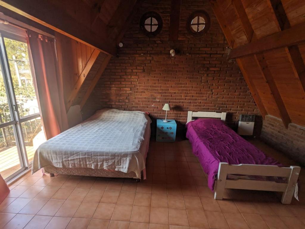 una camera da letto con due letti e un muro di mattoni di La Alpina a Chivilcoy
