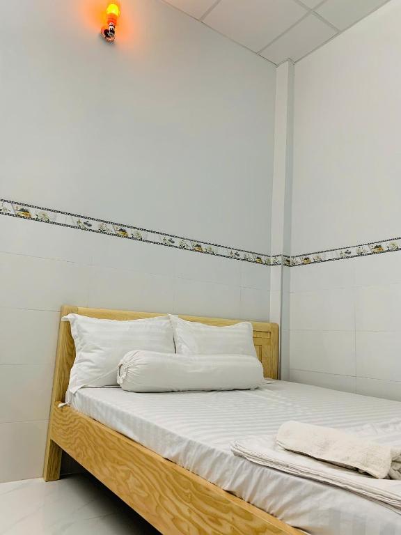 Nhà Nghỉ 79 : غرفة نوم بسرير خشبي مع وسائد بيضاء