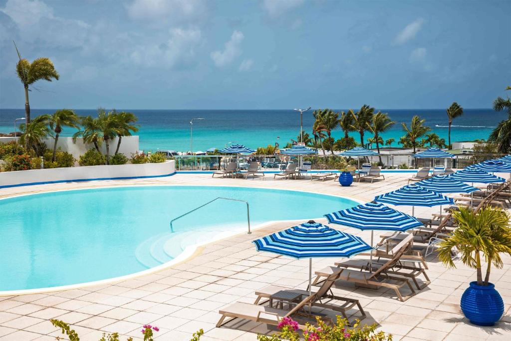 une piscine avec chaises et parasols et l'océan dans l'établissement Royal Islander Club Resort La Terrasse, à Lowlands