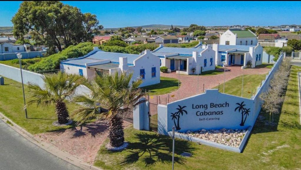 a row of white houses with palm trees and a sign at Long Beach Cabanas in Langebaan