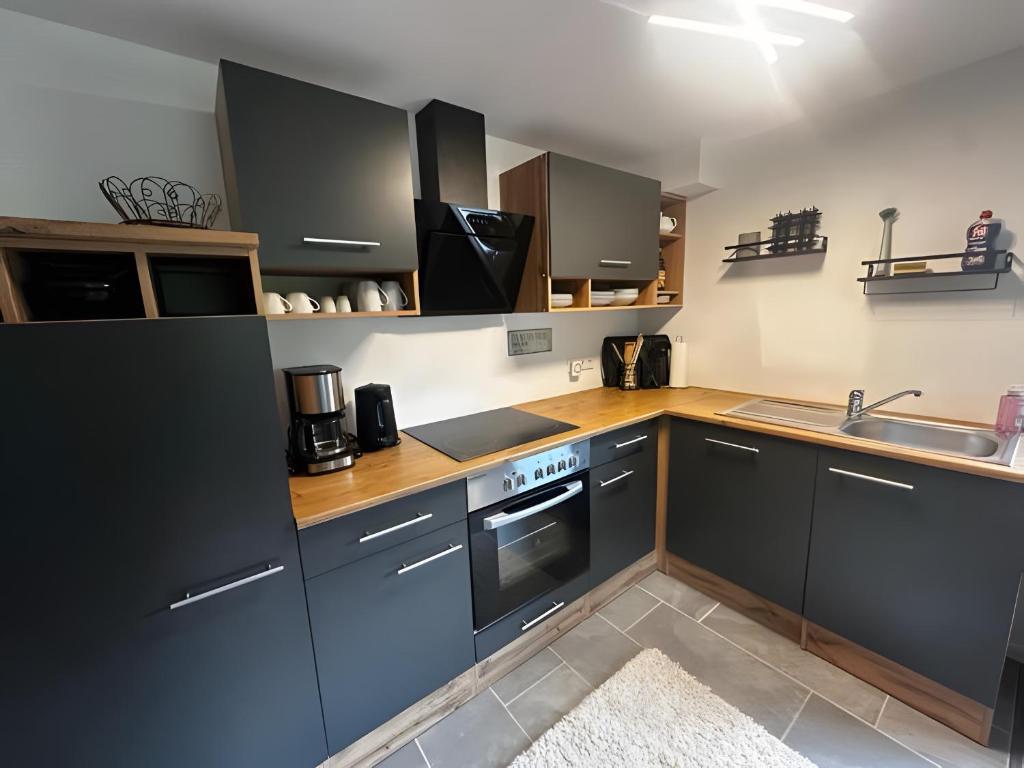 - une cuisine avec des placards noirs et un évier dans l'établissement Ferienwohnung vor dem Zoller, à Boll