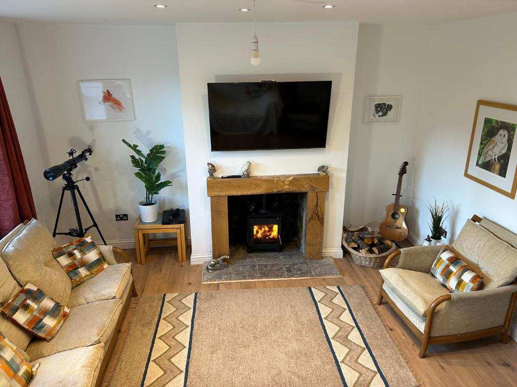a living room with a fireplace and a flat screen tv at Kielder Station Master's House in Kielder