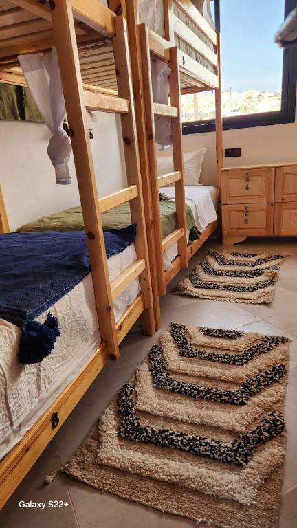 two bunk beds in a room with rugs on the floor at Rock Surf Hostel Taghazout in Taghazout