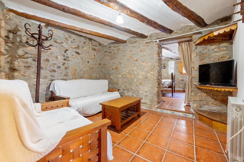 Una sala de estar con dos camas y un televisor. en Casa Rural Masdenverge, en Masdenverge