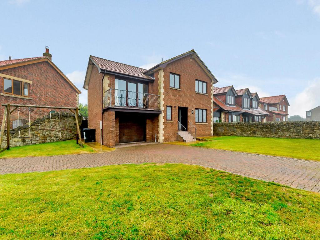 a large brick house with a stone wall at Seaglass House in Beadnell