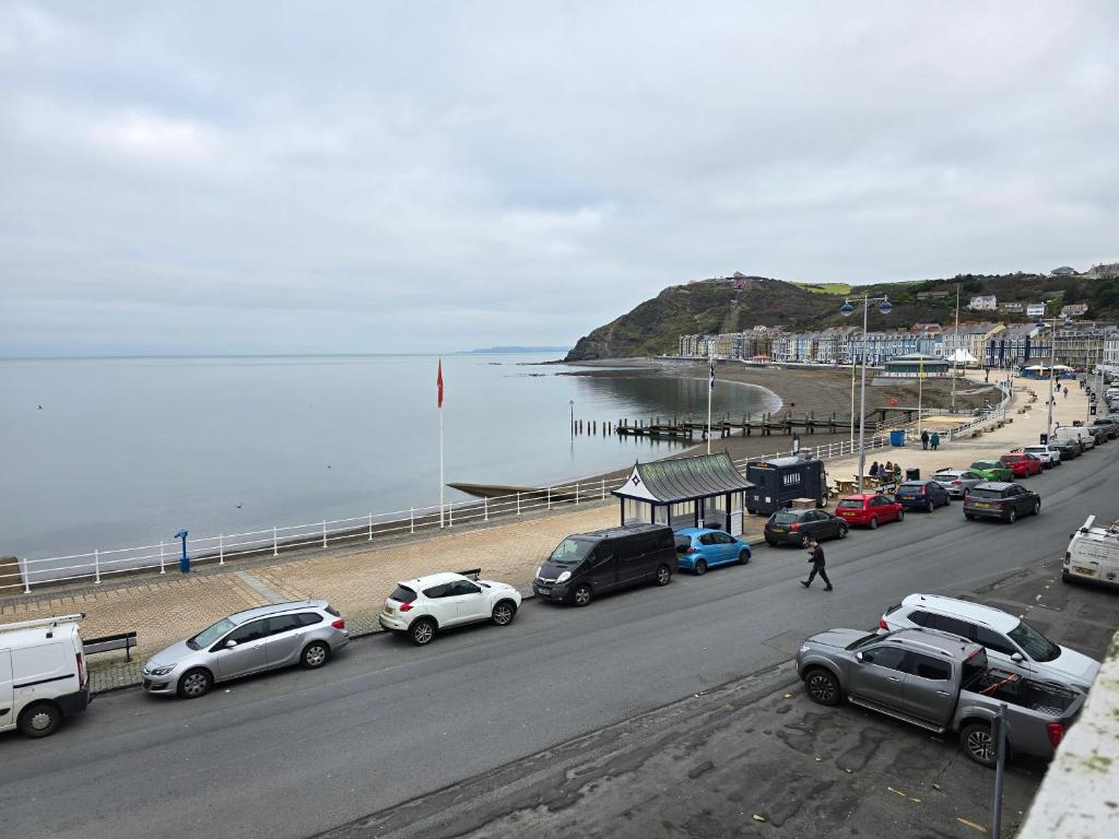 a busy road with cars parked on the beach at Beautiful Seafront 1 bedroomed apartment in Aberystwyth