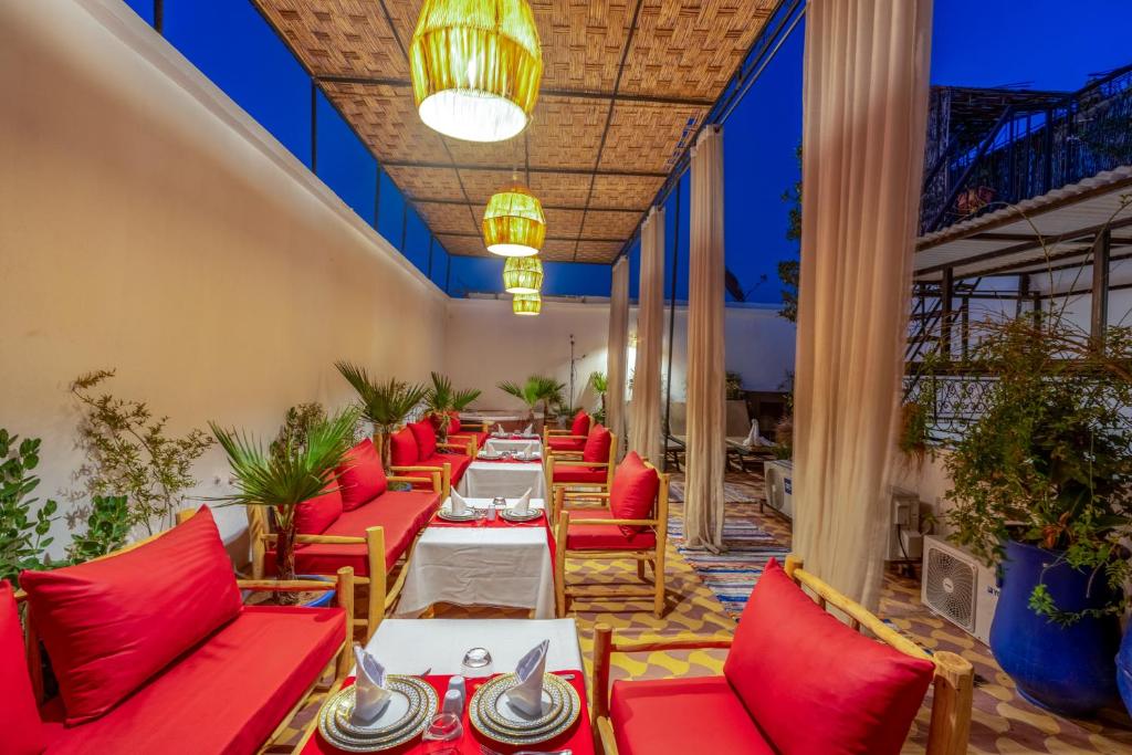 a dining room with red chairs and tables at Riad des remparts Marrakech in Marrakech