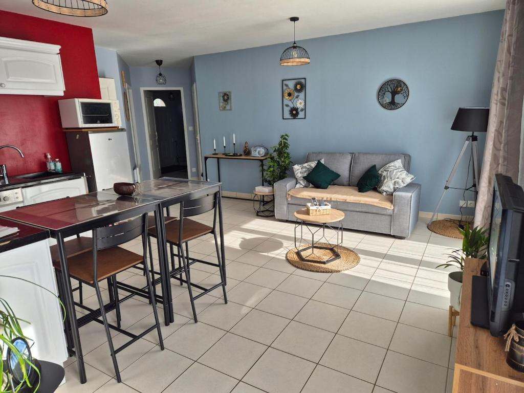 a kitchen and living room with a couch and a table at Maison chaleureuse au calme in Domérat