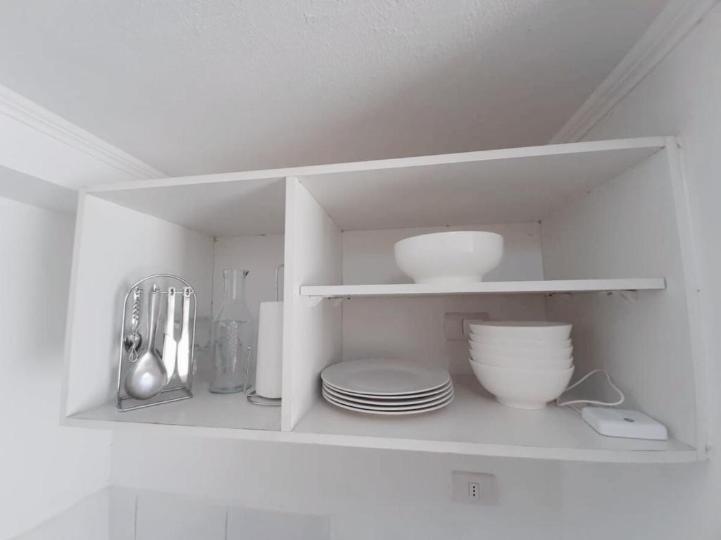 a white cabinet with plates and bowls and utensils at Apartamento moderno - Metro a 3 min - 2 dormitorios in Santiago