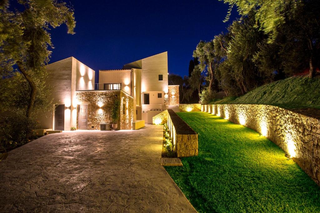 a house with lights on the lawn at night at Golden Bay Suites & Maisonettes in Parga