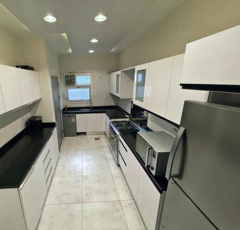 une cuisine avec des armoires blanches et des comptoirs noirs dans l'établissement مدينتي القاهرة الجديدة, à Madinaty