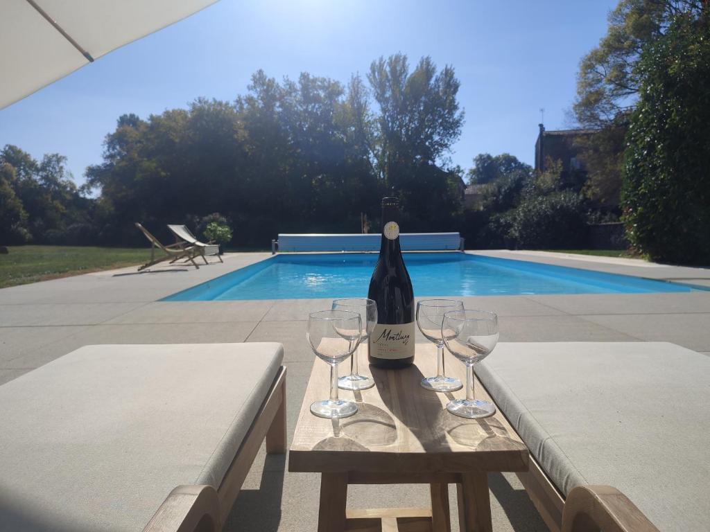 a bottle of wine sitting on a table with wine glasses at Séjour d'exception au Moulin de la Vernède avec piscine, ruisseau, climatisation et parking in Conques-sur-Orbiel