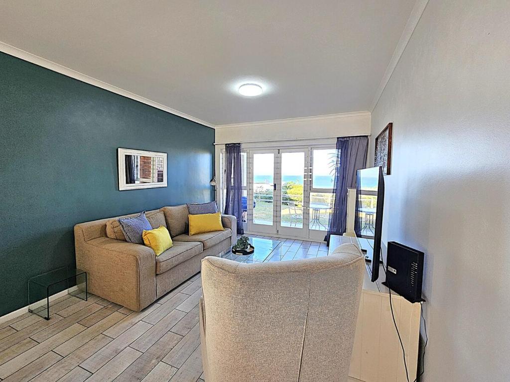 a living room with a couch and a tv at Dolphin Nook 29 in Gqeberha