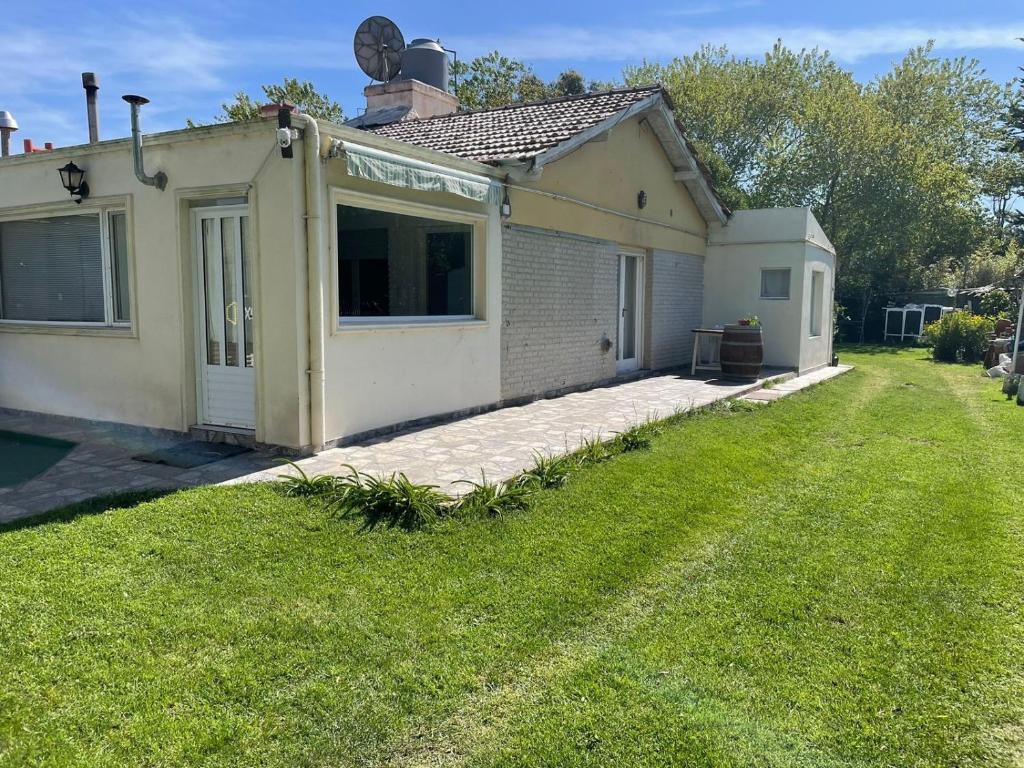 una casa con césped delante en Departamento en Mar Chiquita, en Balneario Mar Chiquita