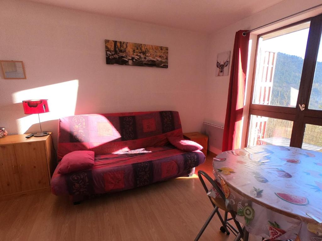 a living room with a couch and a table at Studio plein sud avec vue magnifique in Château-Bernard