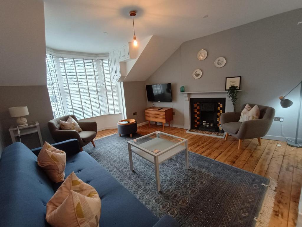 Una sala de estar con un sofá azul y una chimenea. en Nos-da, en Menai Bridge