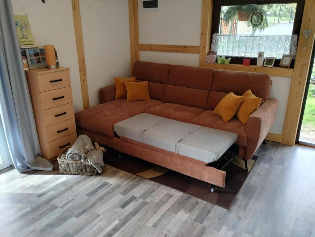 Nowy WiecにあるDomek nad stawemのリビングルーム(ブラウンソファ、黄色い枕付)