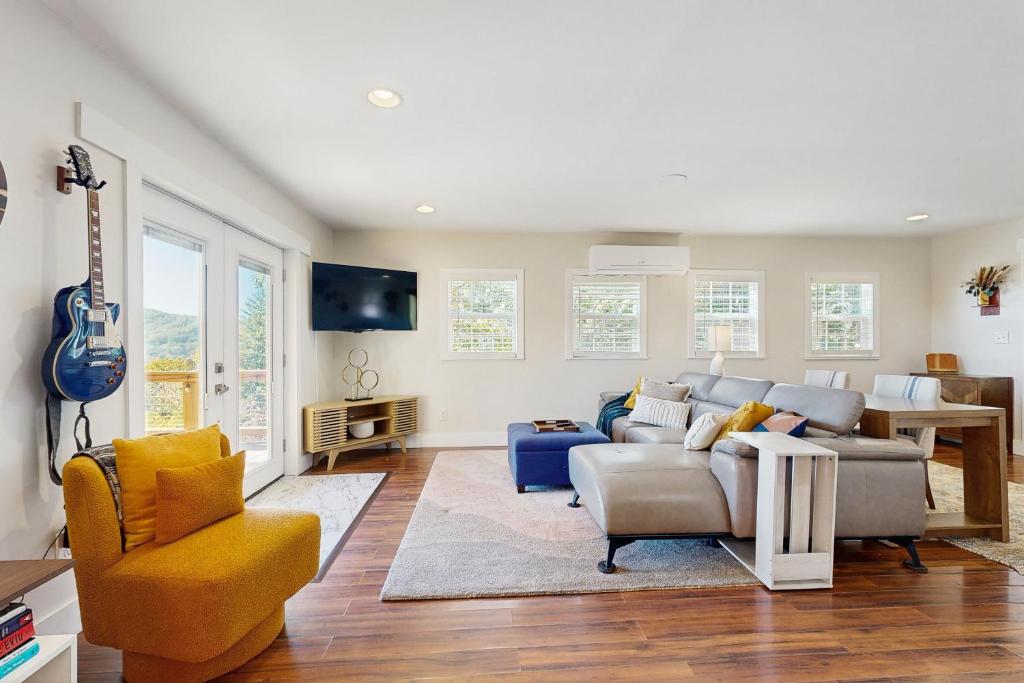 un soggiorno con divano, sedie e chitarra di Raven Haven a Clyde