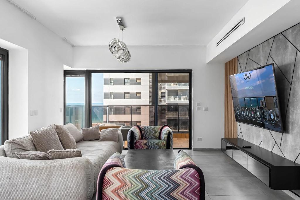 a living room with a couch and a flat screen tv at O&O Group-Charming 4BR APT with Stellar Sea View in Bat Yam