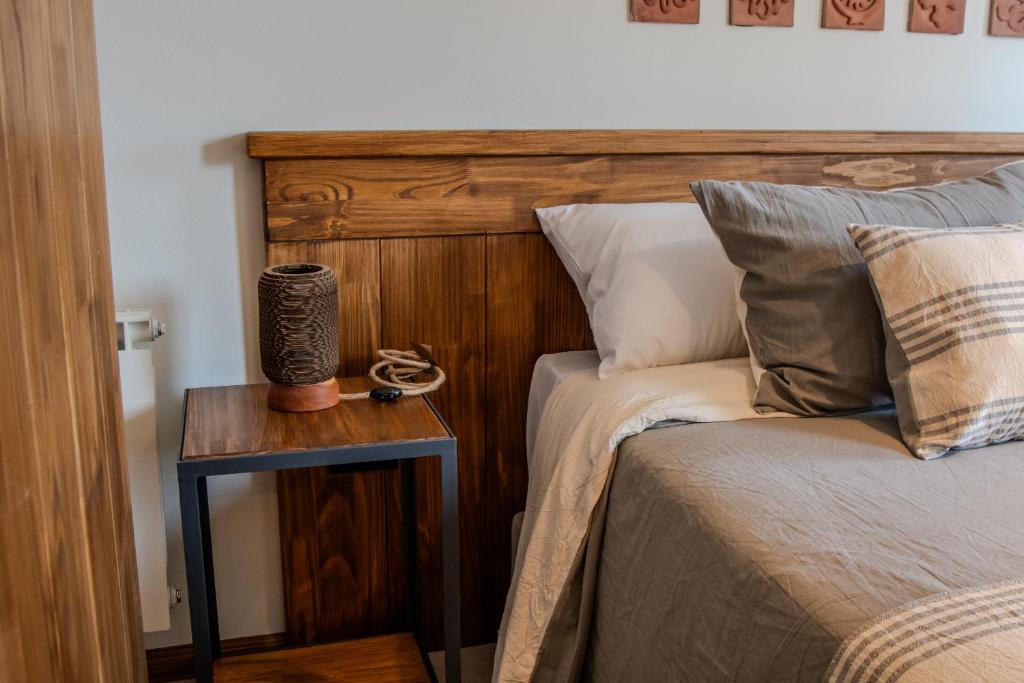 a bed with a wooden headboard next to a side table at Agua de Tajamar in Alta Gracia