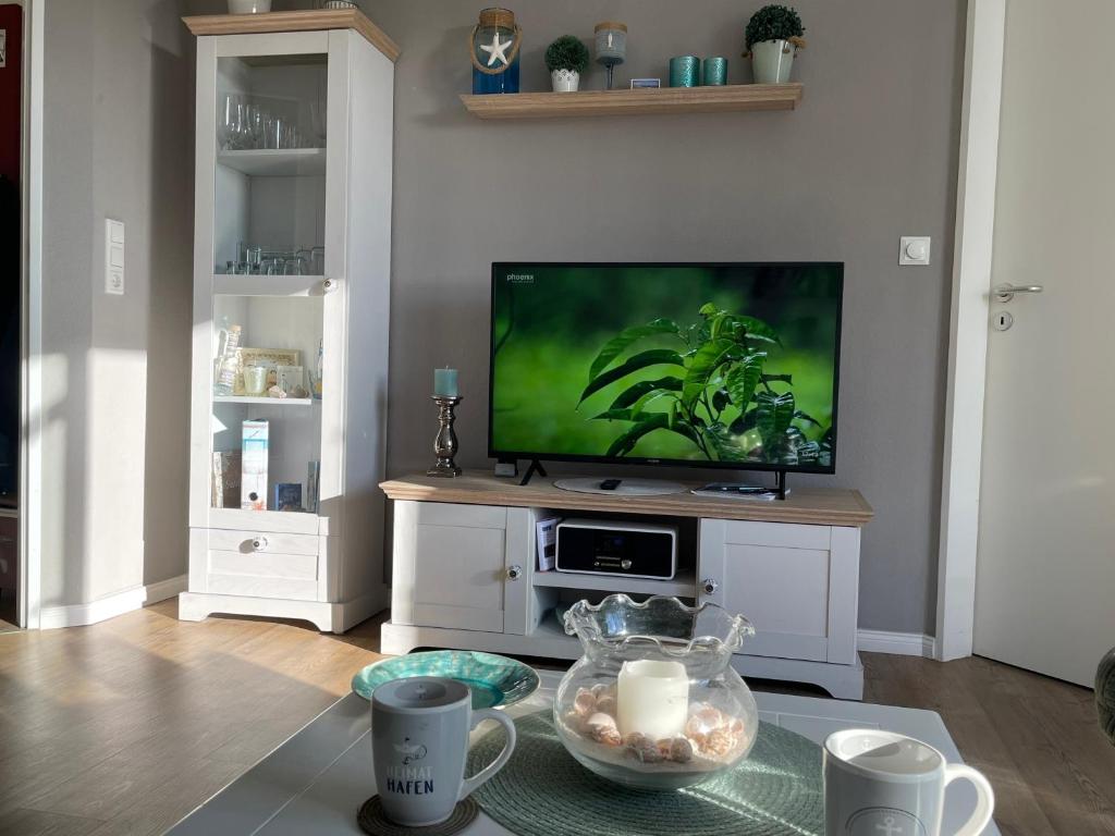 ein Wohnzimmer mit einem TV und einem Tisch mit Kerzen in der Unterkunft "Haus Atlantic" - Wohnung "StrandGut" in Grömitz