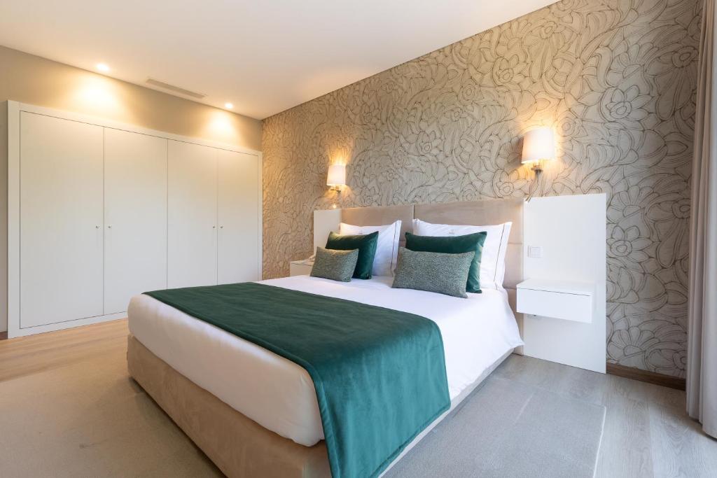 a bedroom with a large white bed with green sheets at Stella Braga Aparthotel in Braga