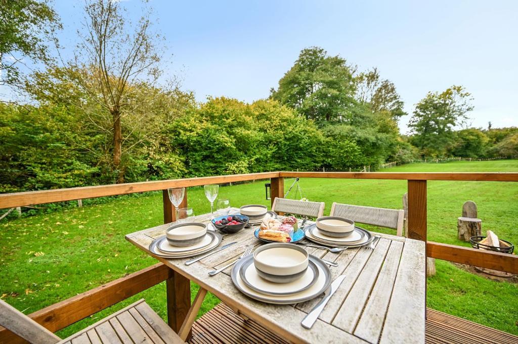 a wooden table with plates of food on a deck at Stag Shepherds Hut in Hartfield