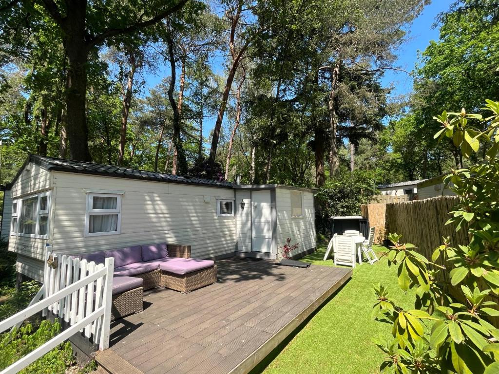 a tiny caravan with a deck in a yard at Forest Cabin - Waldhütte Tante Truus Veluwe - Recreatiepark 't Veluwshof in Hoenderloo