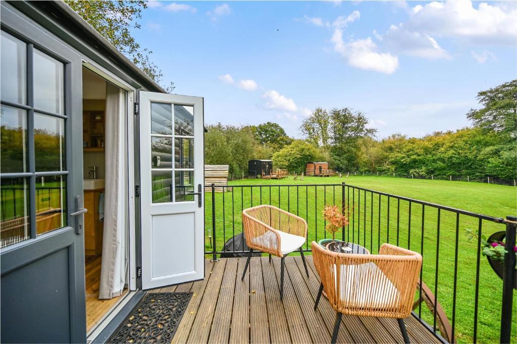 a porch with two chairs and a door at Badger Shepherds Hut in Hartfield
