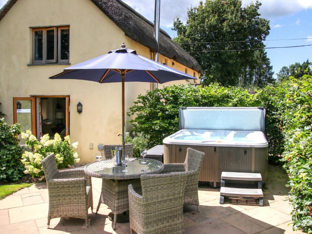 a table and chairs with a hot tub and an umbrella at 2 bed in Torrington 49589 in Roborough