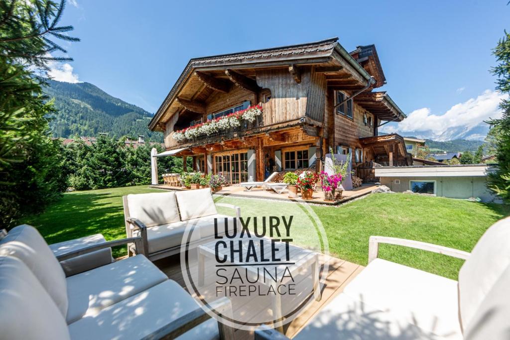 a log house with a table and chairs in front of it at Harmony Deluxe Chalet, Sauna & Fireplace by Belle-Stay in Reith bei Kitzbühel