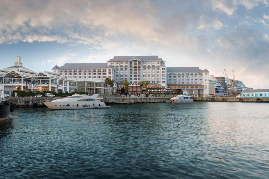 two boats in the water in front of buildings at InterContinental Hotels Table Bay Cape Town by IHG in Cape Town