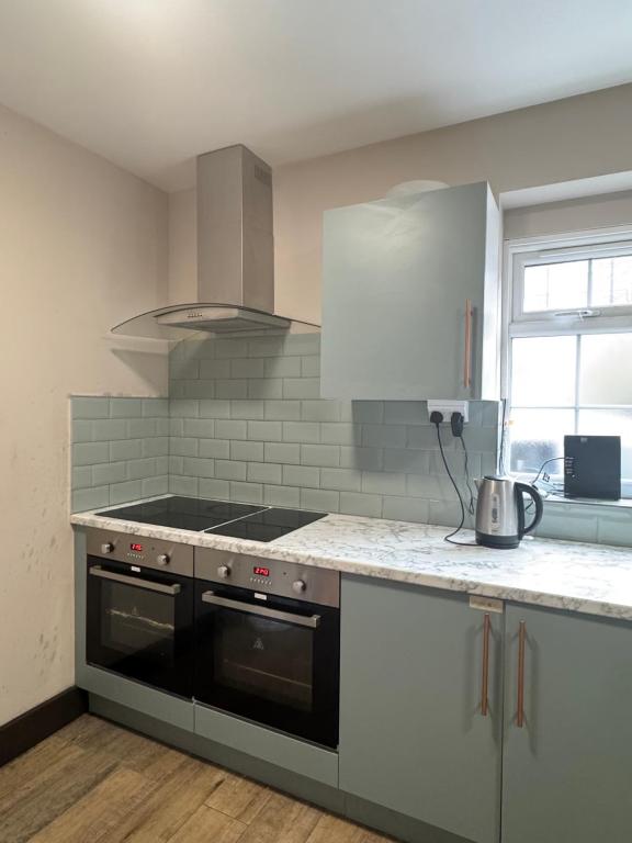 a kitchen with a stove and a counter top at En-suite studios near Wembley Stadium in Northwood