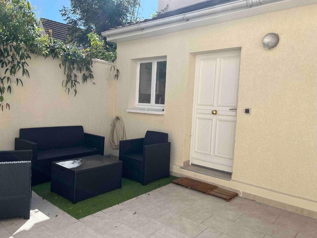 un patio avec deux chaises bleues et une porte blanche dans l'établissement Petite maison cosy proche de La Défense, à Nanterre