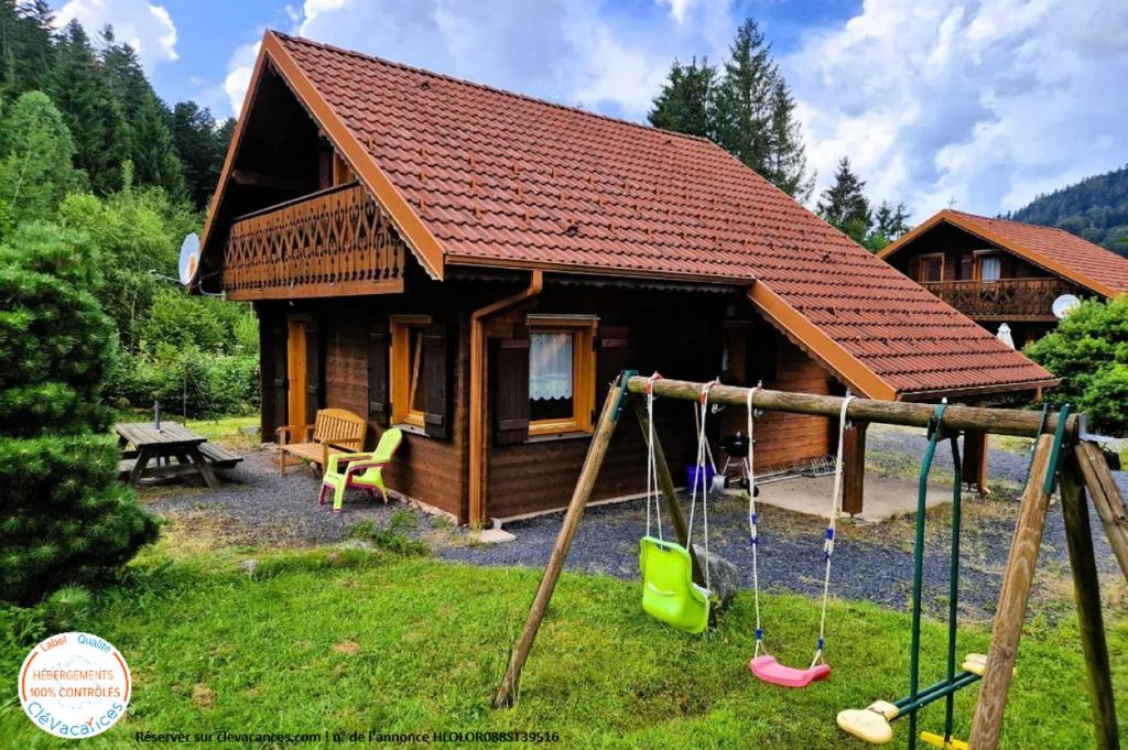 une cabane en rondins avec des balançoires devant elle dans l'établissement Chalet Biazot, à Xonrupt-Longemer