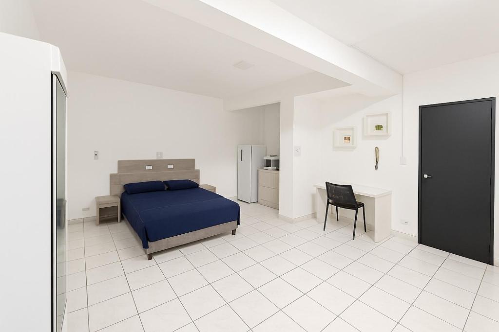 Un dormitorio con una cama, un escritorio y una silla. en Smart Loft Premium Moderno e Inteligente no Centro Unidade 04, en Presidente Prudente