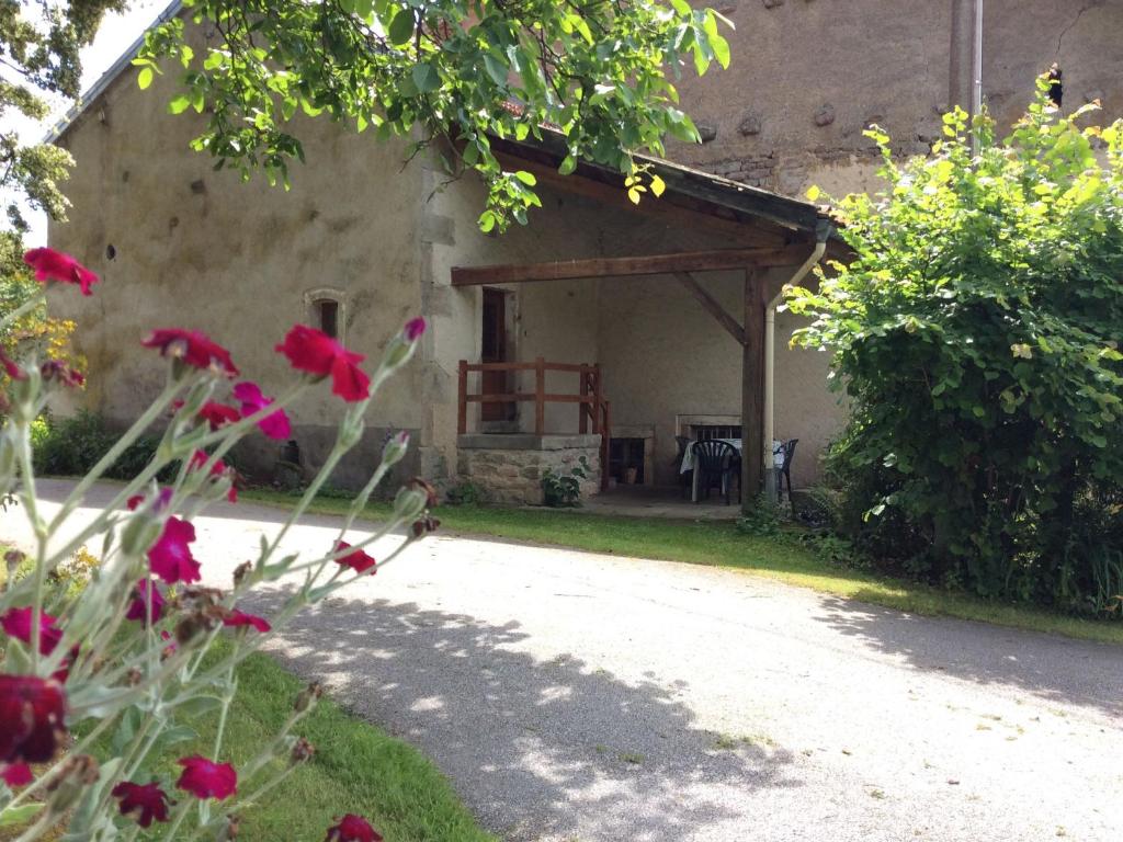 a garden with red flowers in front of a building at Maison de charme en pierres, proche de la nature, idéale pour balades, proche Épinal - FR-1-589-73 in Girancourt