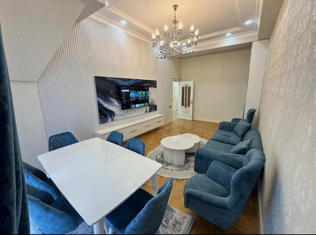 a living room with a white table and blue chairs at 2-Bedroom Apartment in Sumqayyt